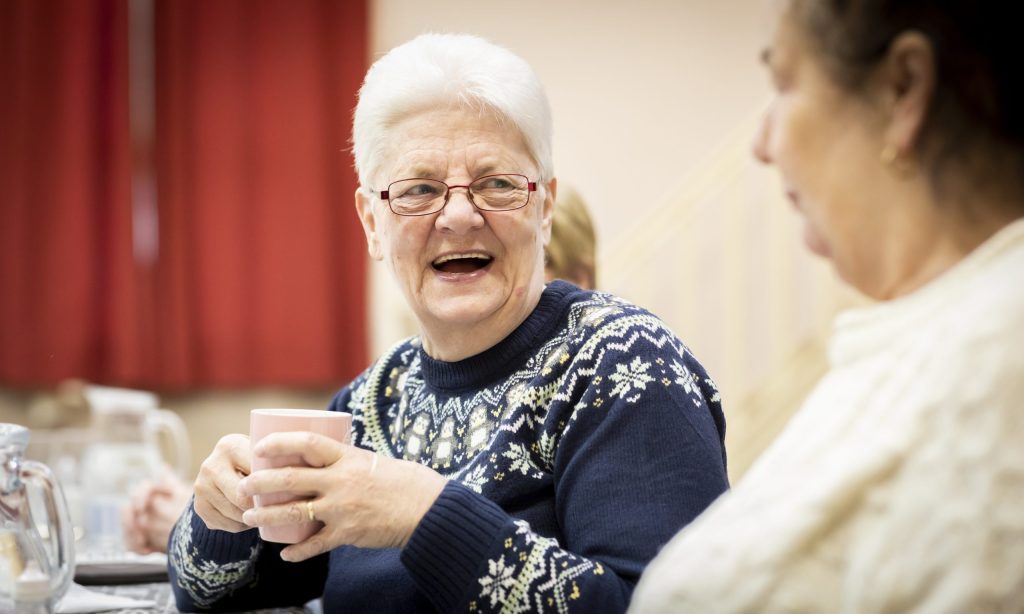 Older lady laughing with a cup of coffee